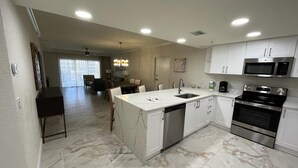 A modern kitchen with white cabinetry, a central island, stainless steel appliances, and a marble floor. - Westgate Vacation Villas (Kissimmee)