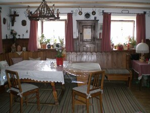 A dining room with a wooden table and chairs, a bench, and a chandelier.