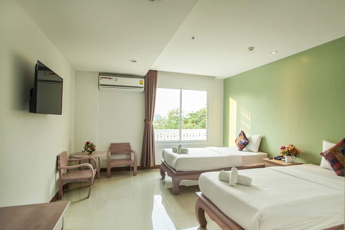 A hotel room with a bed, a desk, a chair, a TV, and a window with curtains.