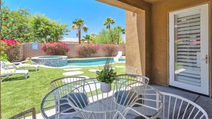Un patio con piscina, sillas de descanso y una mesa con sillas.