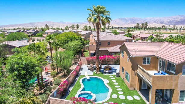 Zona residencial con piscina, palmeras y casas con techos de tejas rojas.