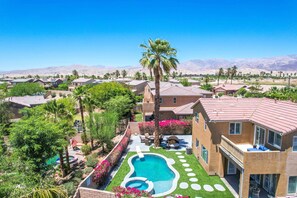 Zona residencial con piscina, palmeras y casas con techos de tejas rojas.