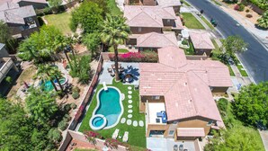 Vista aérea de un área residencial con varias casas, una piscina y un césped bien cuidado.