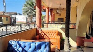 Un balcón con un sofá azul acolchado y un banco naranja también acolchado.