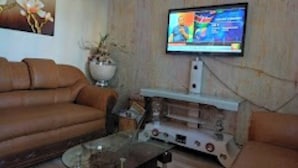 Una sala de estar con un sofá de cuero marrón, una mesa de centro de vidrio y un televisor de pantalla plana montado en una pared de madera.