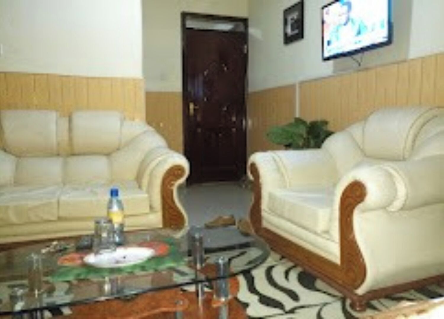 A living room with a sofa, armchairs, a coffee table, and a television on the wall.