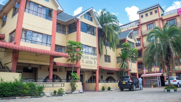 Un hotel de varios pisos con un llamativo letrero que dice "Golden Palace Hotel", con balcones y palmeras.