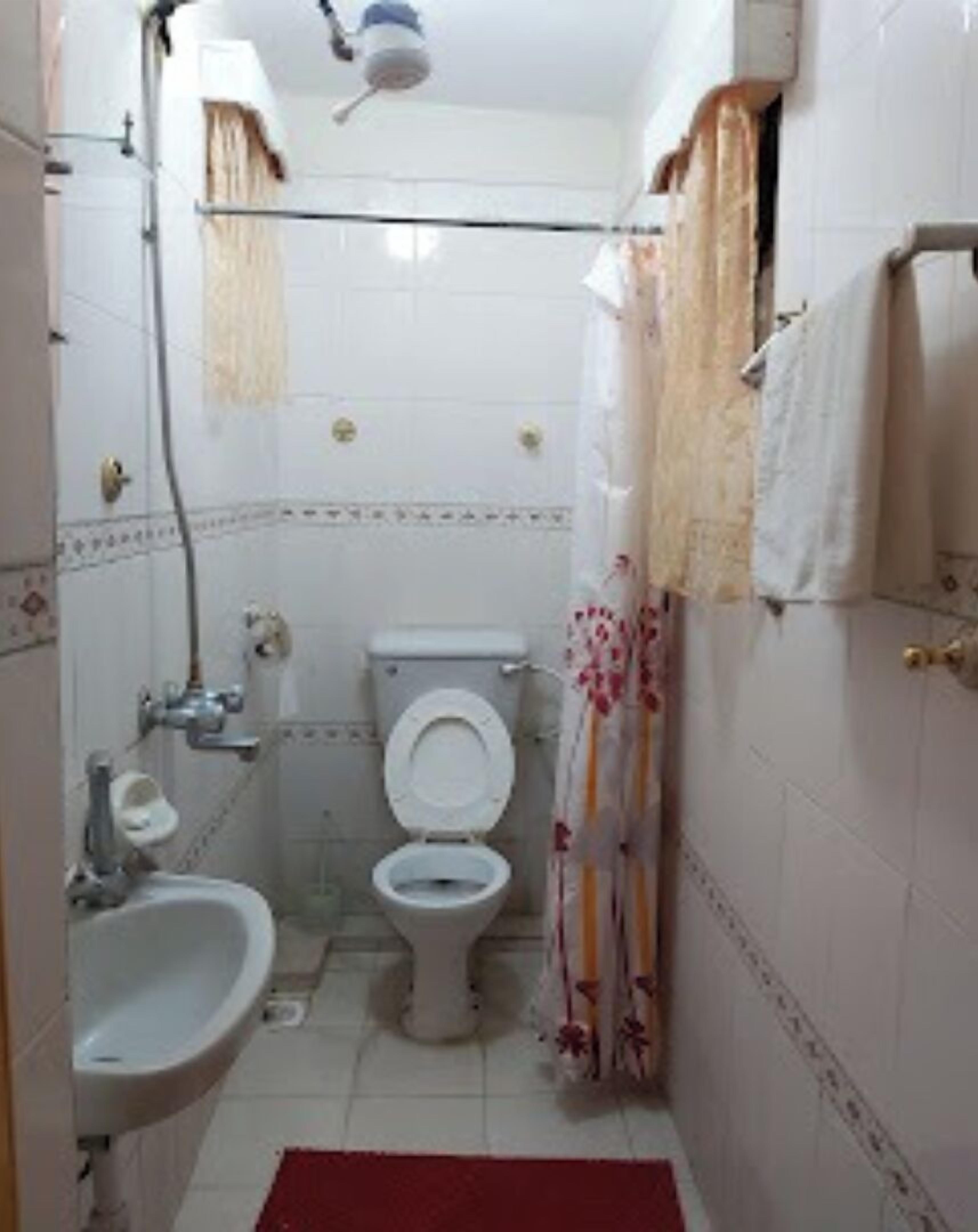 A small bathroom with a toilet, sink, and shower curtain.
