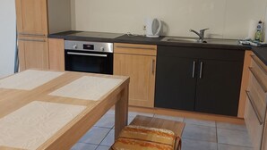 Une cuisine moderne avec une table en bois, un banc, un four encastré, un évier et des placards.