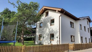 Un bâtiment à deux étages avec de nombreuses fenêtres, une clôture en bois et un trampoline dans la cour.
