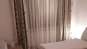 Une chambre d’hôtel avec un lit, une table de chevet et un rideau.