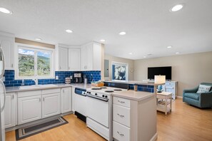 Una cocina moderna con armarios blancos, salpicadero azul y una isla central con estufa.