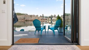 Une terrasse avec deux chaises et une table, donnant sur un lac, avec des maisons en arrière-plan.