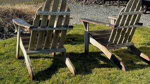 A waterfront property with two Adirondack chairs, a small dock, and a white building with a large window. - Bayfront Tiny Home - Tillamook Bay/Garibaldi (Garibaldi)
