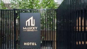 Une grille en métal noir sur laquelle est apposée une enseigne indiquant « M. LUCKY HOTEL » en anglais et en coréen.