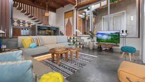 Un salon moderne avec un canapé, une table basse et un téléviseur.