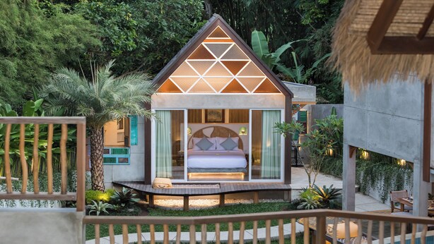 Une chambre moderne aux murs de verre, dotée d’un lit, d’un petit balcon et d’un espace piscine.