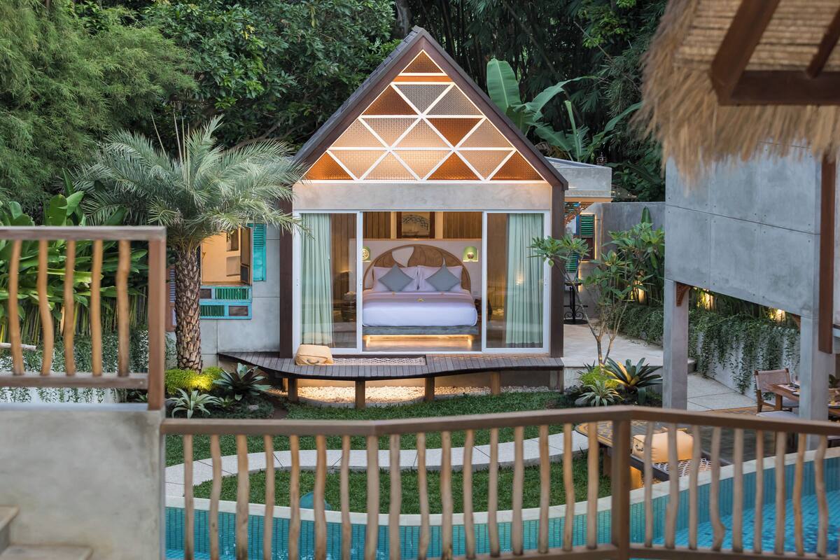 Un dormitorio moderno con paredes de vidrio, una cama, un pequeño balcón y una zona de piscina.