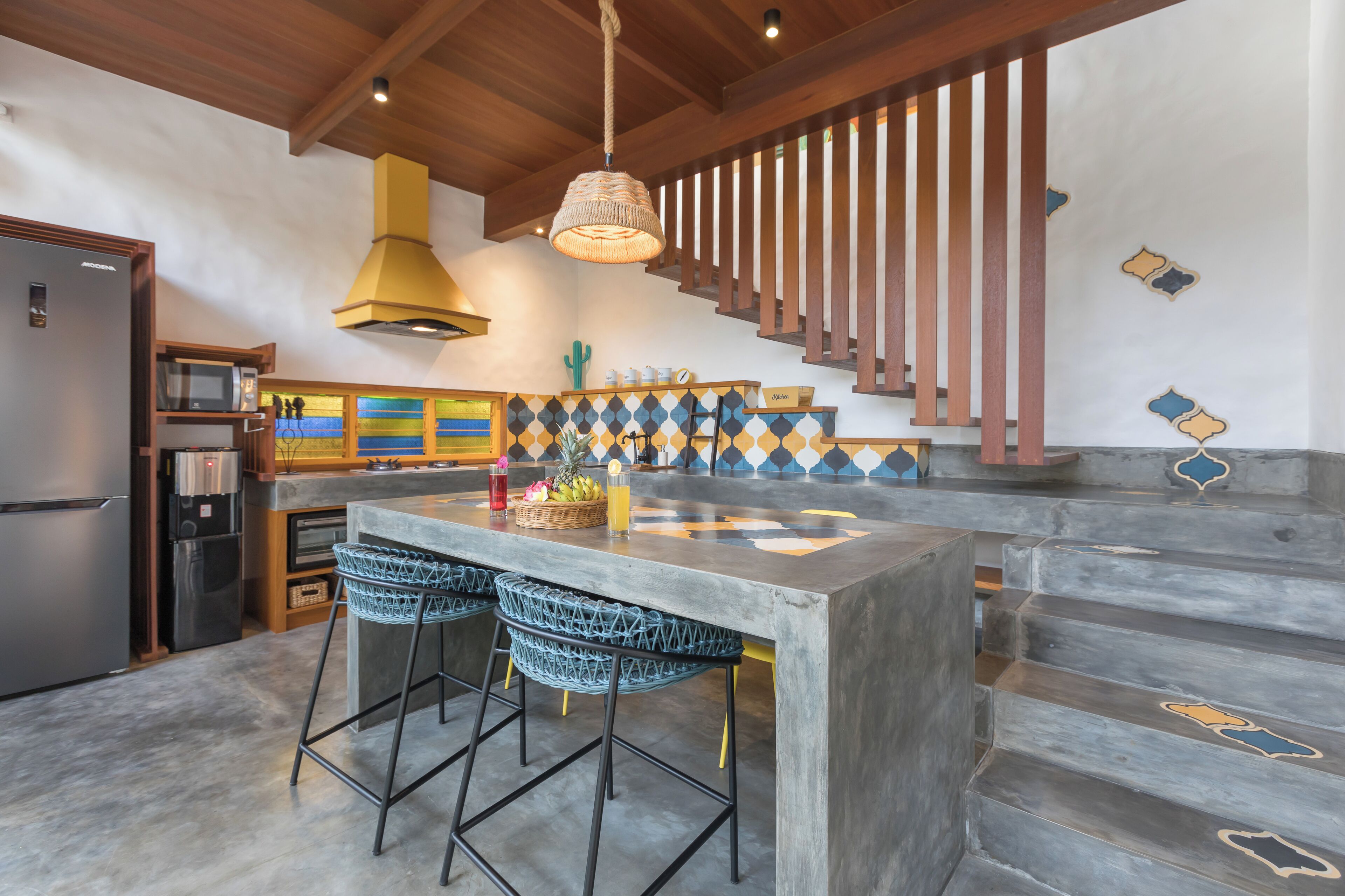 Une cuisine dotée d’un îlot central, de tabourets de bar, d’un escalier et d’un mur décoratif.