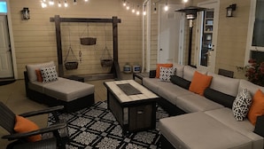 A cozy outdoor seating area with a sofa, chairs, and a patterned rug.