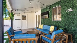 An outdoor seating area with wooden furniture and a green wall.