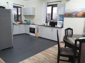 Una cocina con estufa, microondas y armarios. Hay una mesa de comedor con sillas.