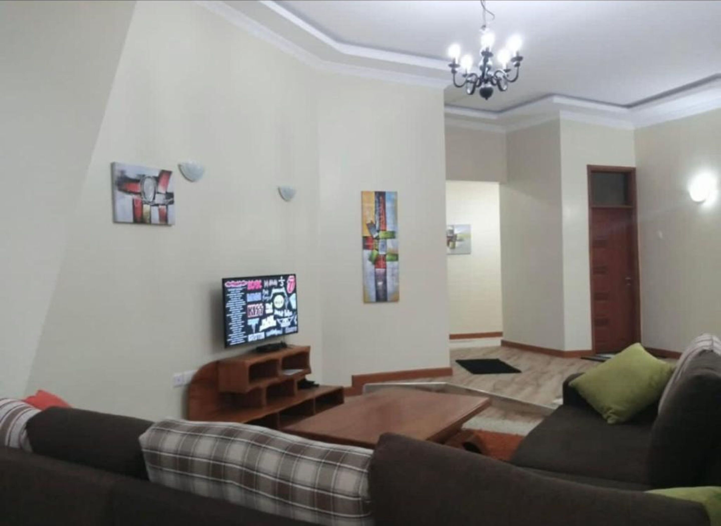 A living room with a sofa, coffee table, TV, and artwork on the walls.