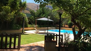 A backyard with a swimming pool, a wooden deck, and a lamp post.