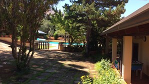A courtyard with a pool, outdoor seating, and a covered area with a table.