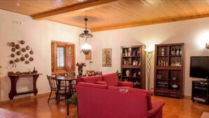 A living room with a red sofa, wooden ceiling, and a television.