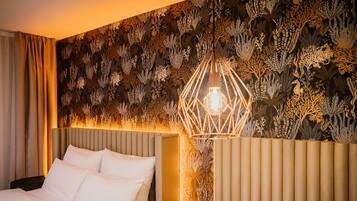 Ein Hotelzimmer mit einem Bett, einem Nachttisch und einer Wand mit einem Blattmuster.