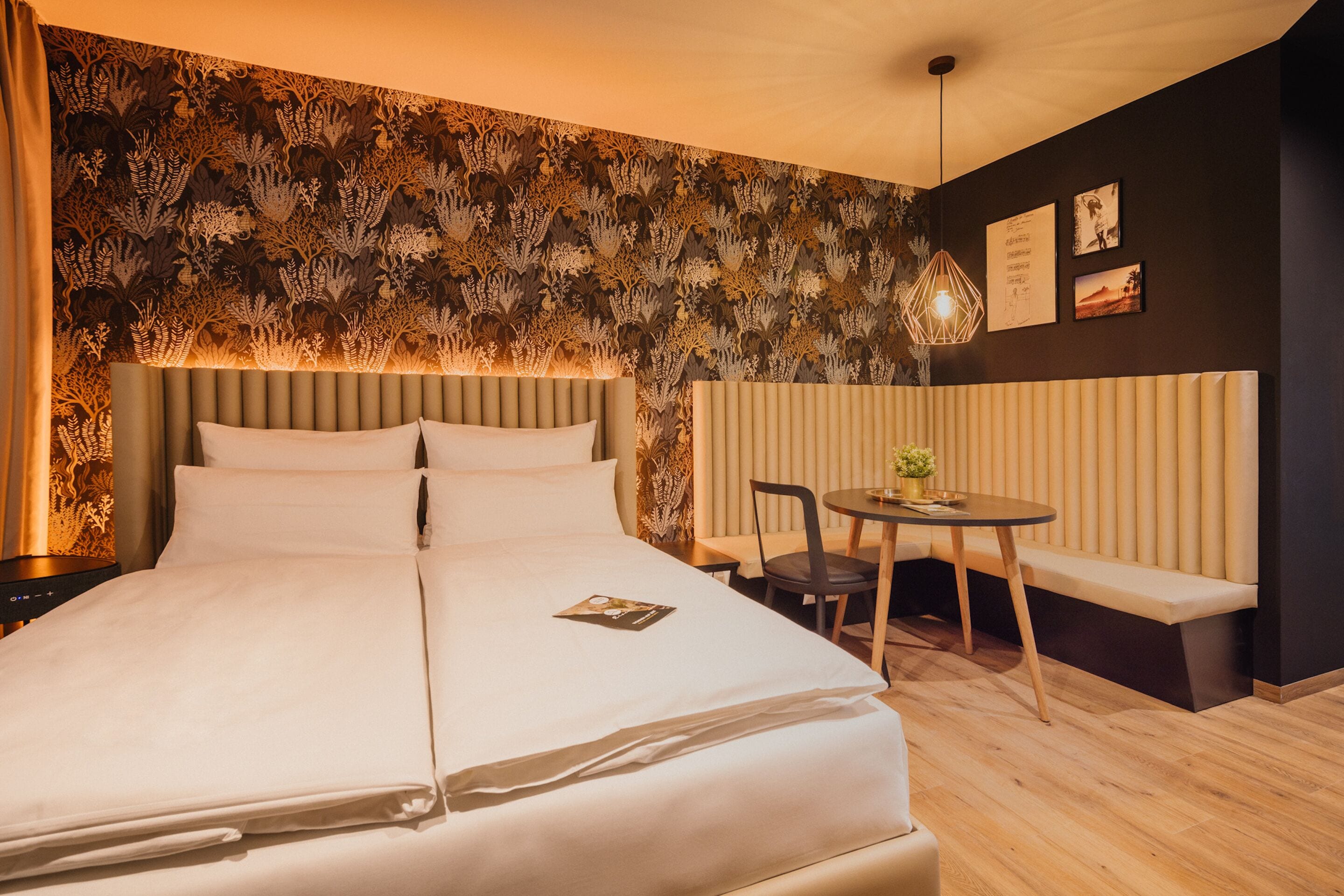 Een hotelkamer met een groot bed, een nachtkastje, een stoel, een klein rond tafeltje en een bank.