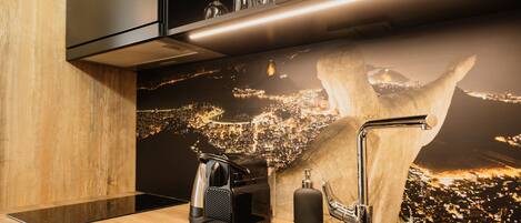 A modern kitchen with a coffee machine, a sink, and a cityscape mural on the wall.