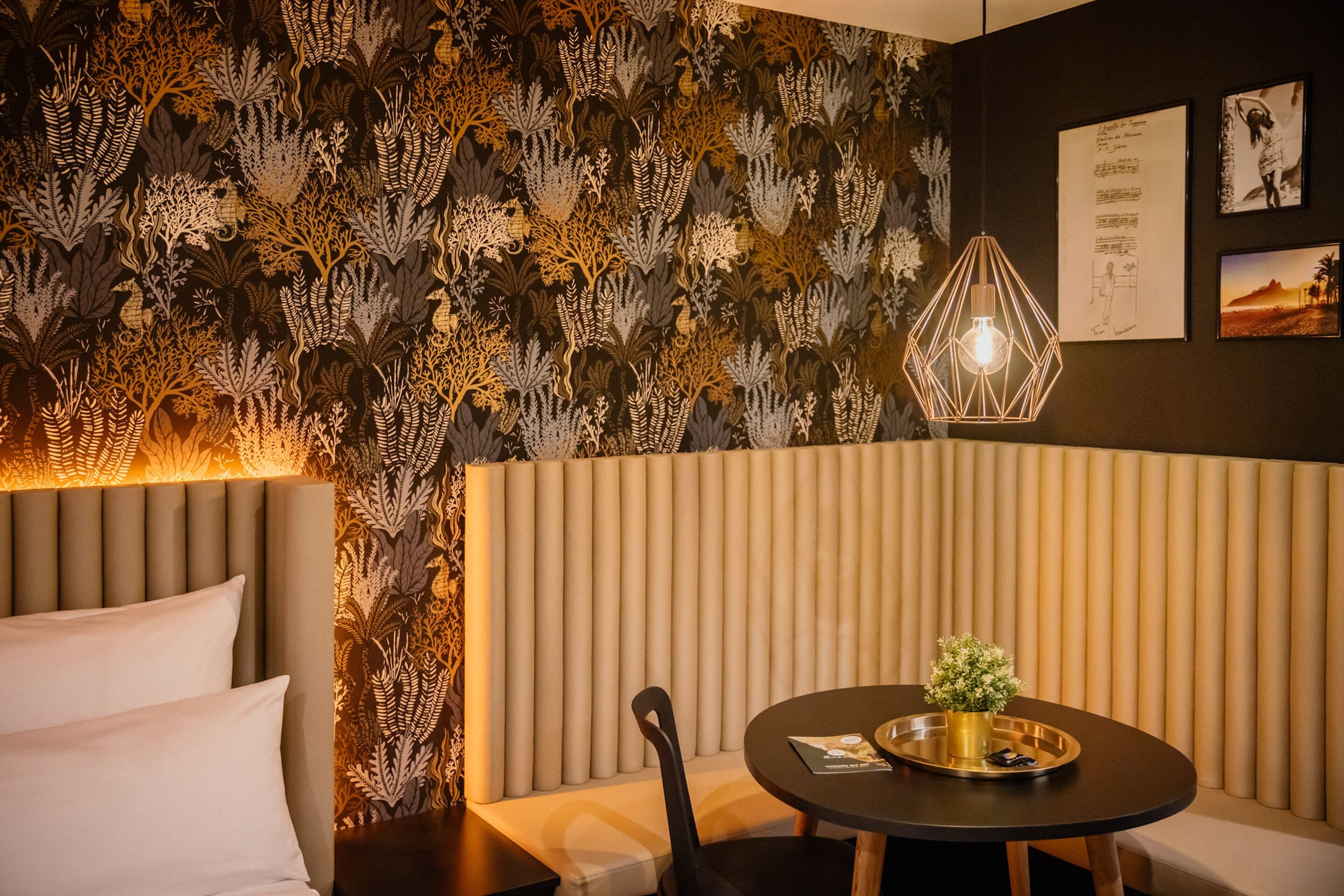 A modern room with a patterned wallpaper, a round table with a tray, and a unique hexagonal light fixture.