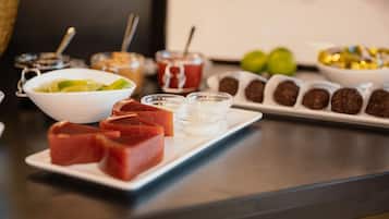 A table with various food items including a plate of meat, a bowl of lime slices, and several small containers of condiments.