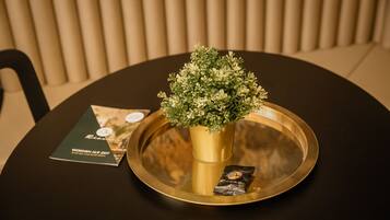 A round table with a gold tray, a small potted plant, and a brochure.