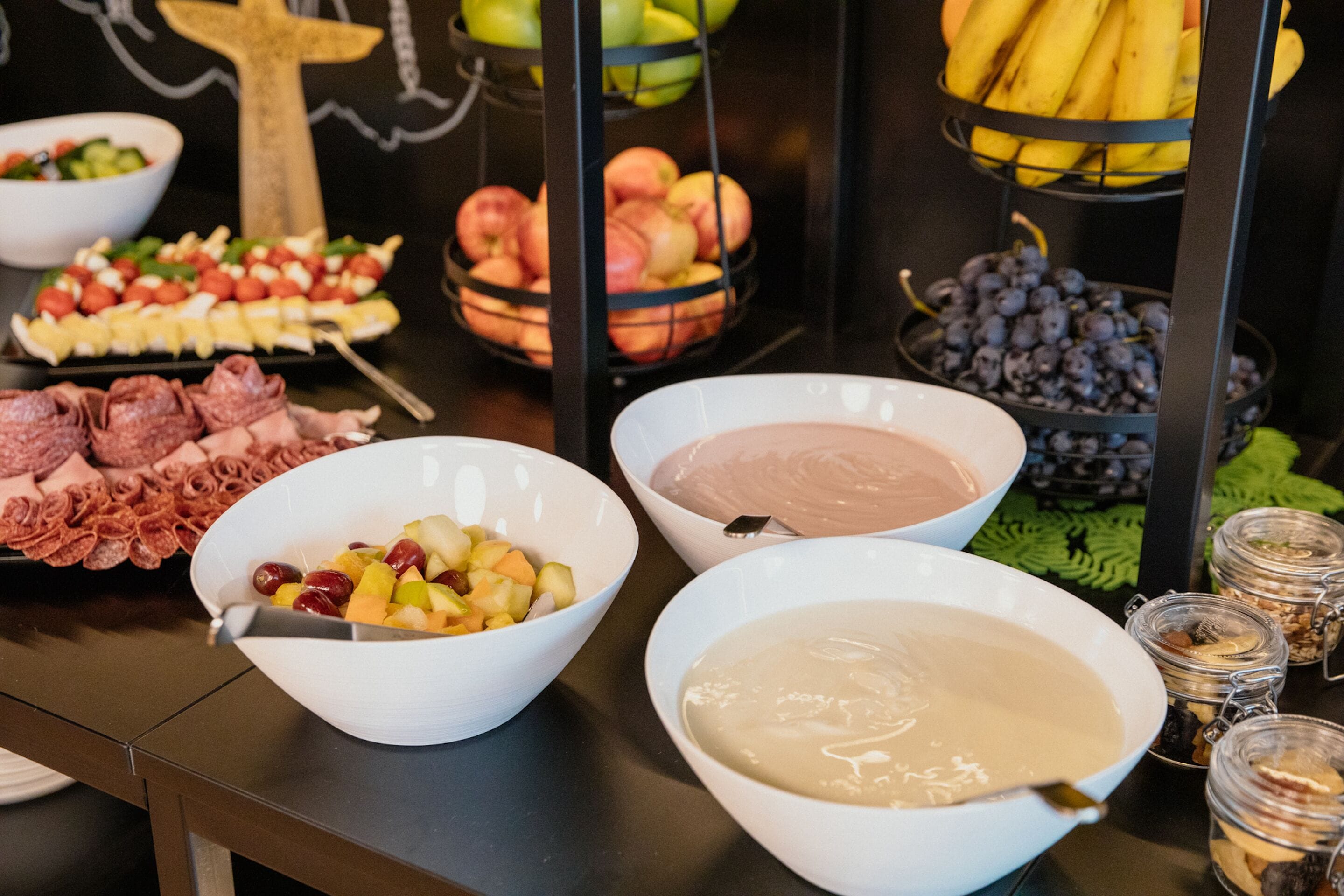 Ein reichhaltiges Buffet mit verschiedenen Speisen, darunter Früchte, Käse und Dips.