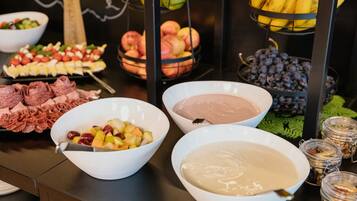 Ein reichhaltiges Buffet mit verschiedenen Speisen, darunter Früchte, Käse und Dips.