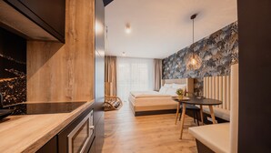 A modern bedroom with a wooden floor, a bed, a bedside table, a hanging light, and a view of the city at night. - Rioca Stuttgart Posto 4 (Stuttgart)