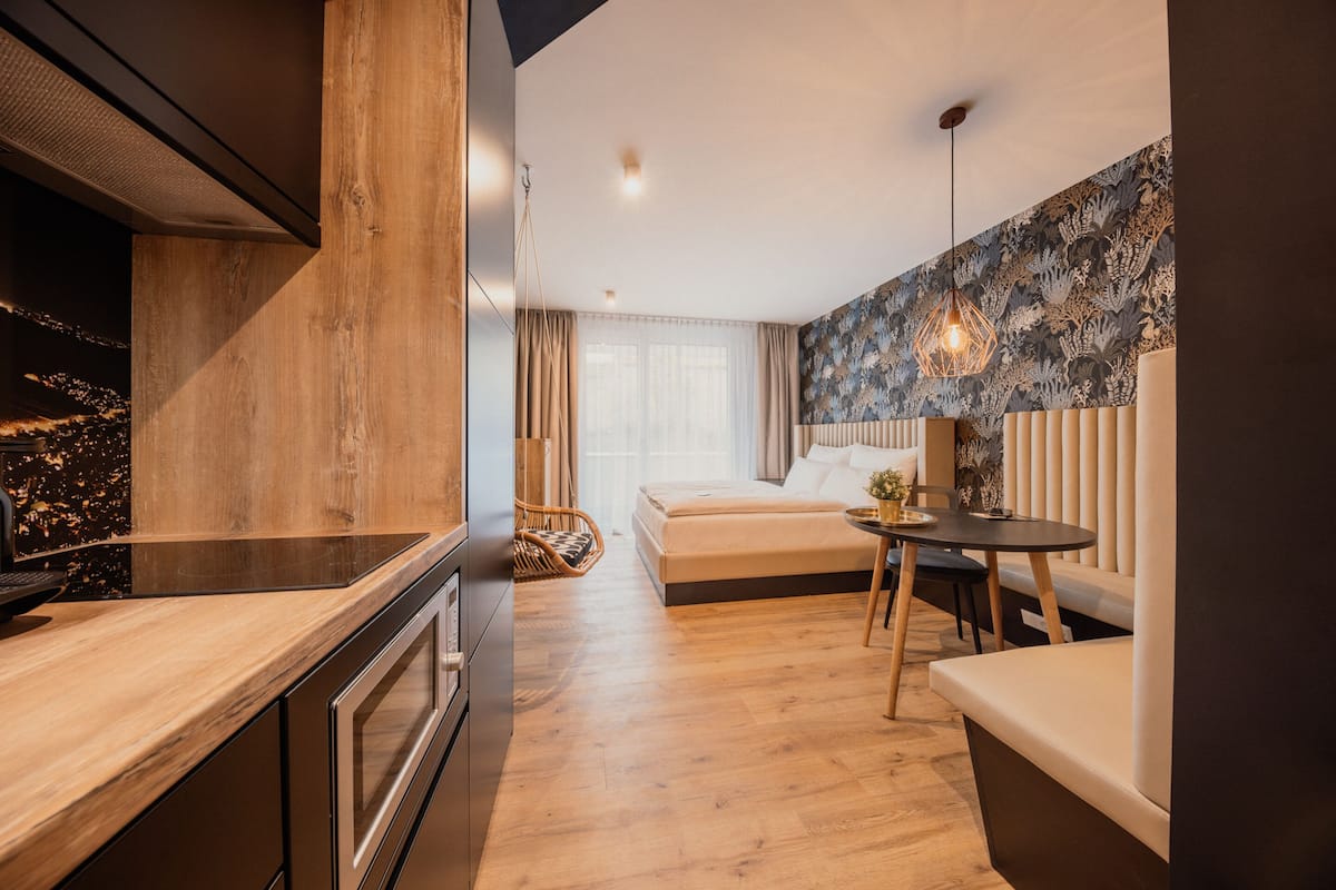 Un dormitorio moderno con suelo de madera, una cama, una mesita de noche, una lámpara colgante y vistas a la ciudad de noche.