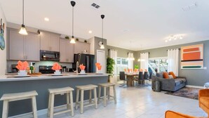 A modern kitchen with a central island, bar stools, and pendant lighting. - Wonderful 5 Bd Private Pool at Storey Lake Resort (Kissimmee)
