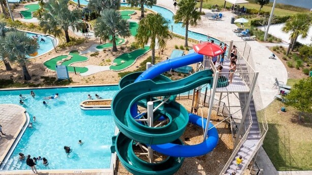 A water park with a large pool, a water slide, and a golf course. - Wonderful 5 Bd Private Pool at Storey Lake Resort (Kissimmee)