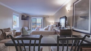 A hotel room with a bed, a desk, a chair, a TV, and a large window with a view. - Spectacular Studio in the Heart of Harbour Town overlooking Harbour & Lighthouse. Dine, Shop, Relax. (Hilton Head Island)