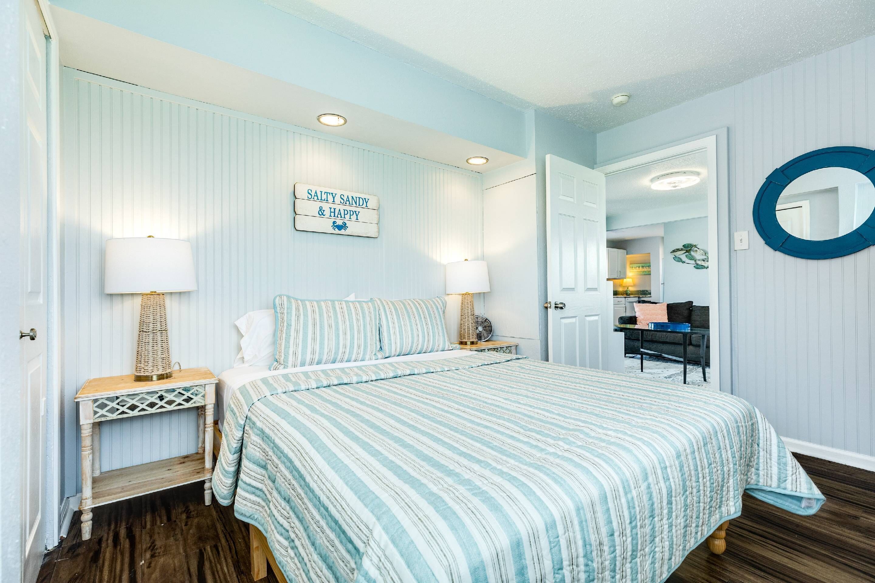 Une chambre à coucher avec un lit, deux tables de chevet, une lampe, un tableau accroché au mur et un miroir.