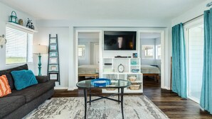 Un salon avec un canapé, une table basse, un téléviseur et une bibliothèque.