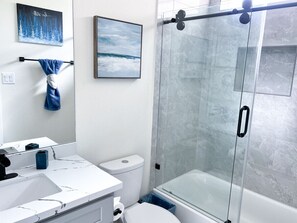 A modern bathroom with a glass shower enclosure, a white sink, and a toilet. - 4 BR Townhome w/ Rooftop + Skyline View (Houston)