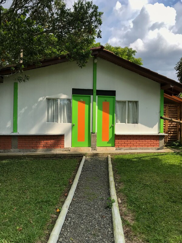 Un edificio con dos puertas, un sendero de grava y un área con césped.