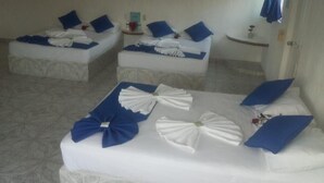 A hotel room with three beds, each with blue pillows and white linens. - Hotel Paraíso Kora (Aticama)