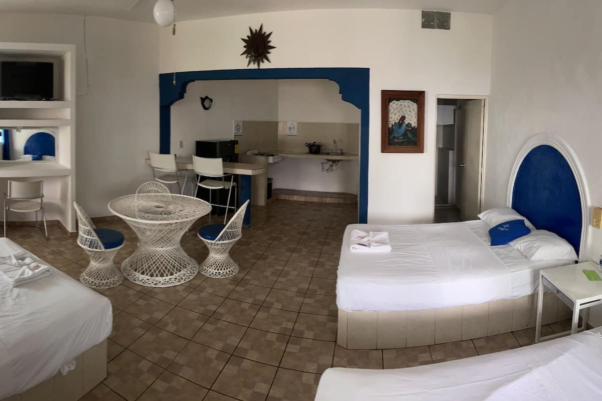 Ein Hotelzimmer mit zwei Betten, einem Schreibtisch, einem Stuhl und einem kleinen Tisch.