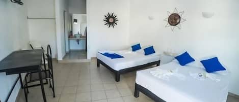 A hotel room with two single beds, a desk, and a chair.
